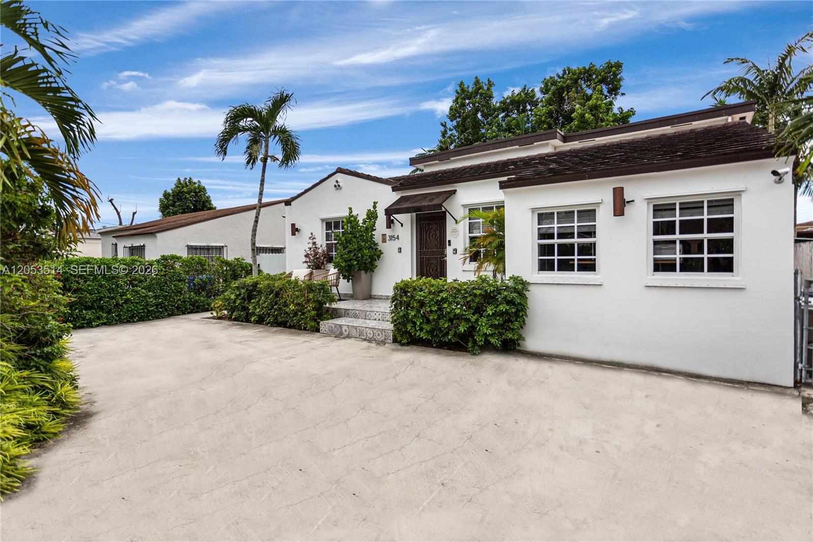 A white single-story house with a concrete driveway, palm trees, and a tiled entryway — 3154 SW 5th St, Miami FL 33135, MIAMI, FL