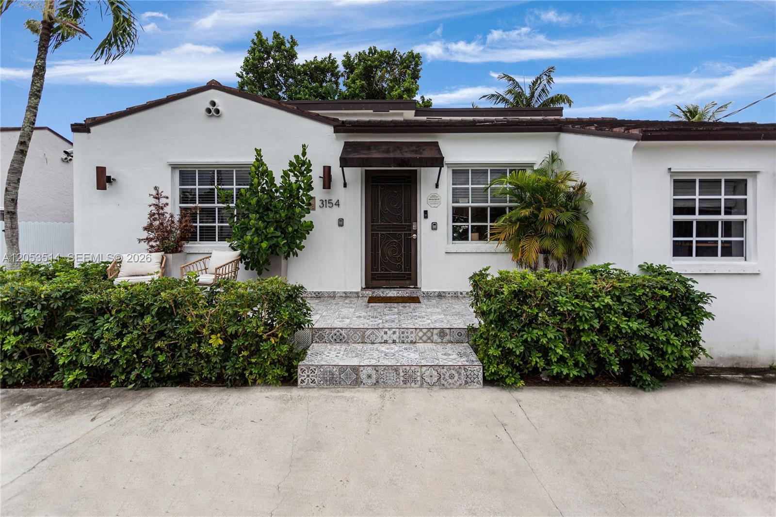 The exterior of a white, single-story house features a tiled entryway and decorative metal door — 3154 SW 5th St, Miami FL 33135, MIAMI, FL