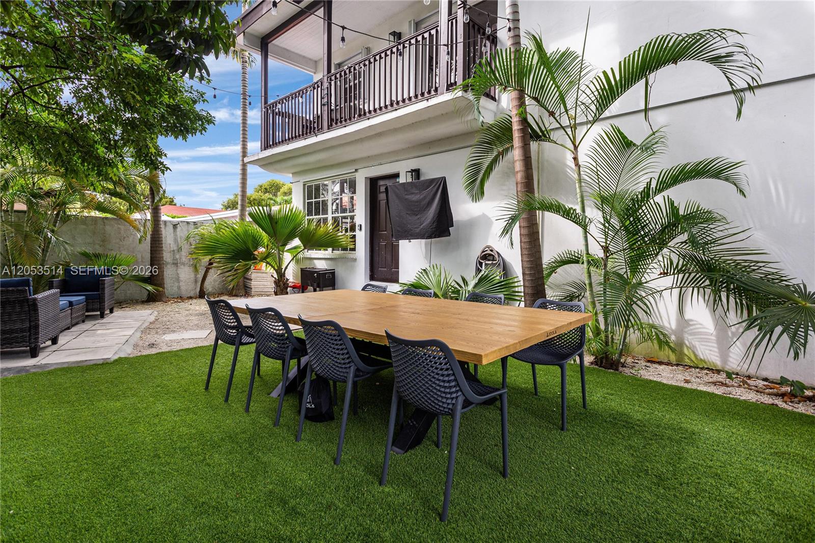 A wooden dining table with black chairs sits on artificial turf in a backyard — 3154 SW 5th St, Miami FL 33135, MIAMI, FL