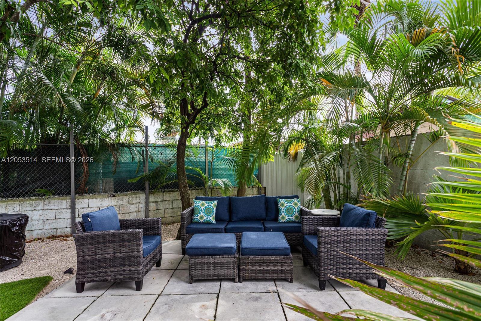 A patio features wicker furniture with blue cushions set on concrete pavers under trees — 3154 SW 5th St, Miami FL 33135, MIAMI, FL
