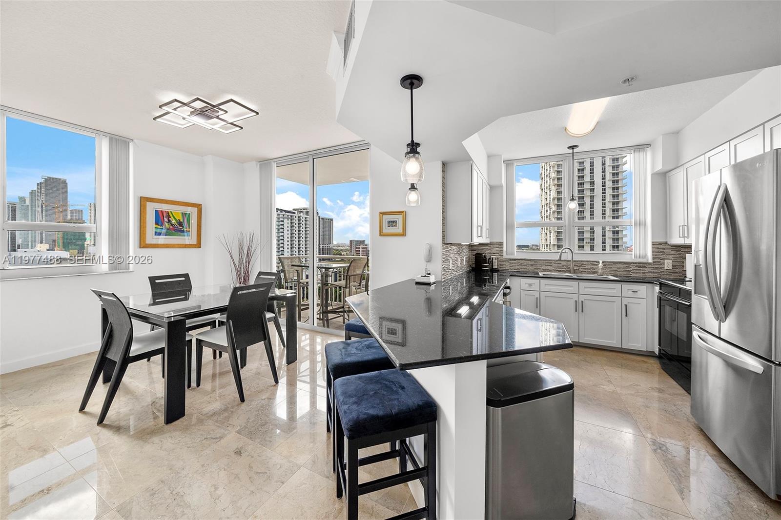 A modern kitchen and dining area features white cabinetry, black countertops, and floor-to-ceiling windows — 2000 N Bayshore Dr # 1502, Miami FL 33137, MIAMI, FL