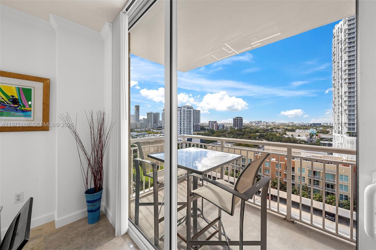 A balcony with a glass-topped table and two chairs overlooks a city skyline — 2000 N Bayshore Dr # 1502, Miami FL 33137, MIAMI, FL