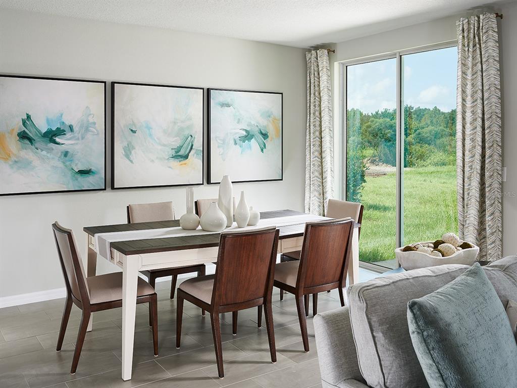 A dining room features a wooden table, six chairs, abstract wall art, and sliding glass doors — 4500 EAGLE PERCH COURT, ST CLOUD, FL