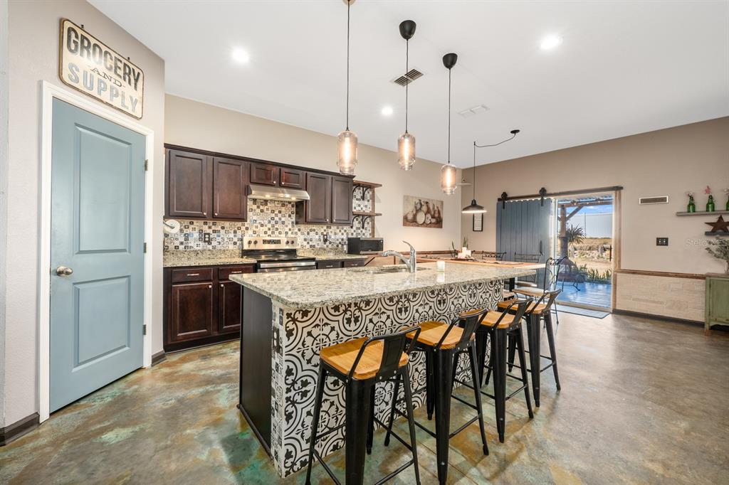 A kitchen features a patterned tile island, dark wood cabinets, and stained concrete floors — 16434 WINDING BLOSSOM DRIVE, GROVELAND, FL