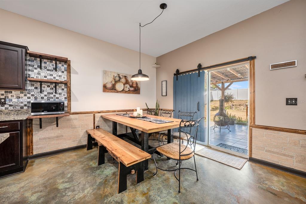 A dining area features a wooden table, bench, metal chairs, and a sliding barn door — 16434 WINDING BLOSSOM DRIVE, GROVELAND, FL