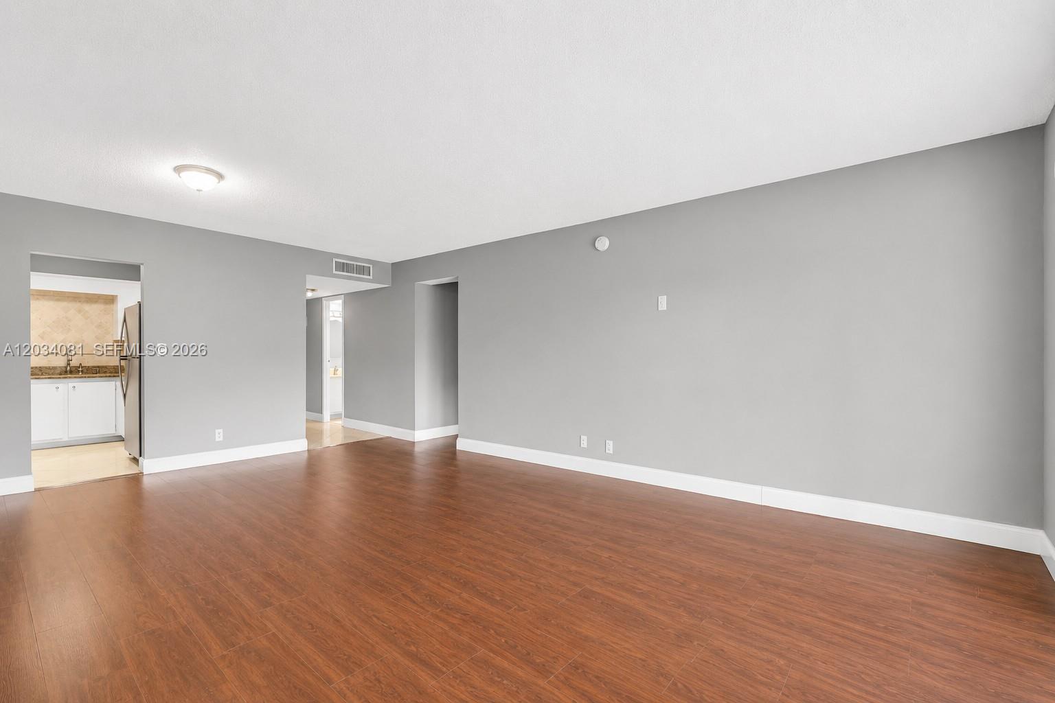 An empty room with gray walls, white trim, and wood-look flooring — 5961 N Falls Cir Dr # 309, Lauderhill FL 33319, LAUDERHILL, FL