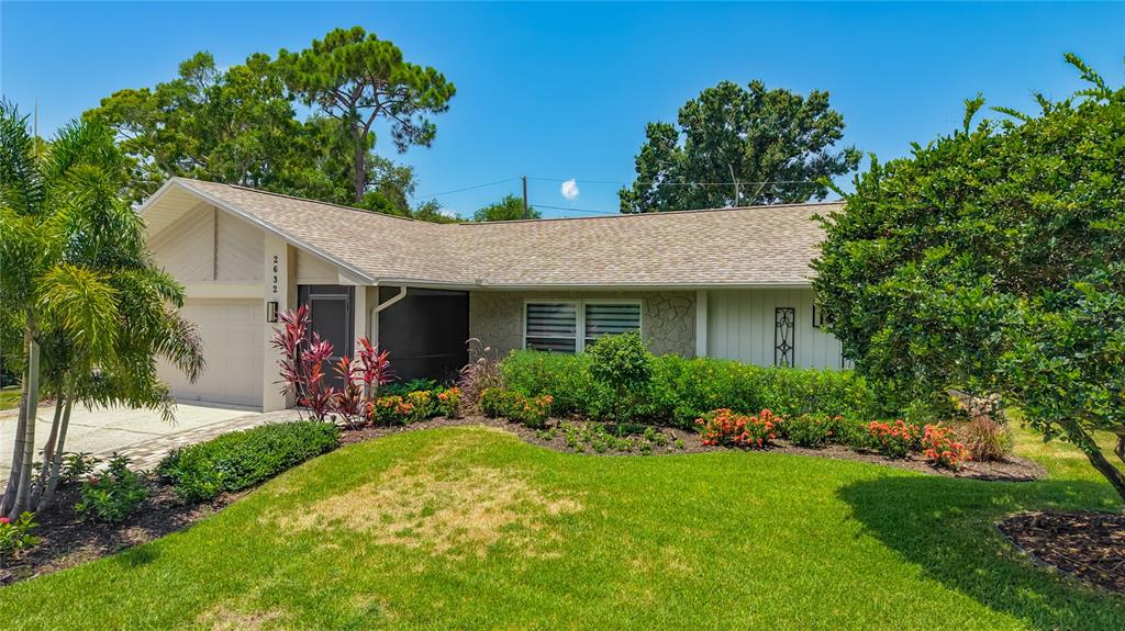 A single-story house with a light-colored exterior, a paved driveway, and a landscaped front yard — 2632 CAMILLE DRIVE, PALM HARBOR, FL