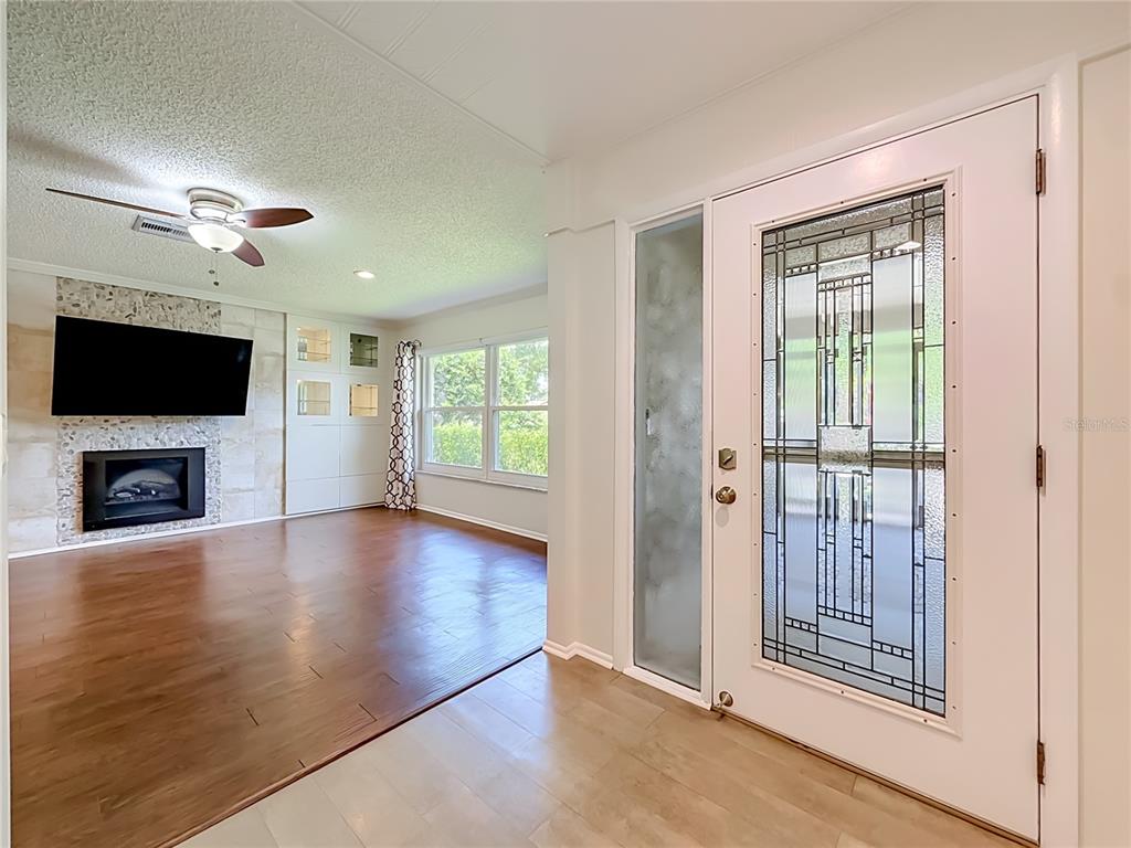 A living room with a fireplace and wood floors is visible through an entryway door — 2632 CAMILLE DRIVE, PALM HARBOR, FL