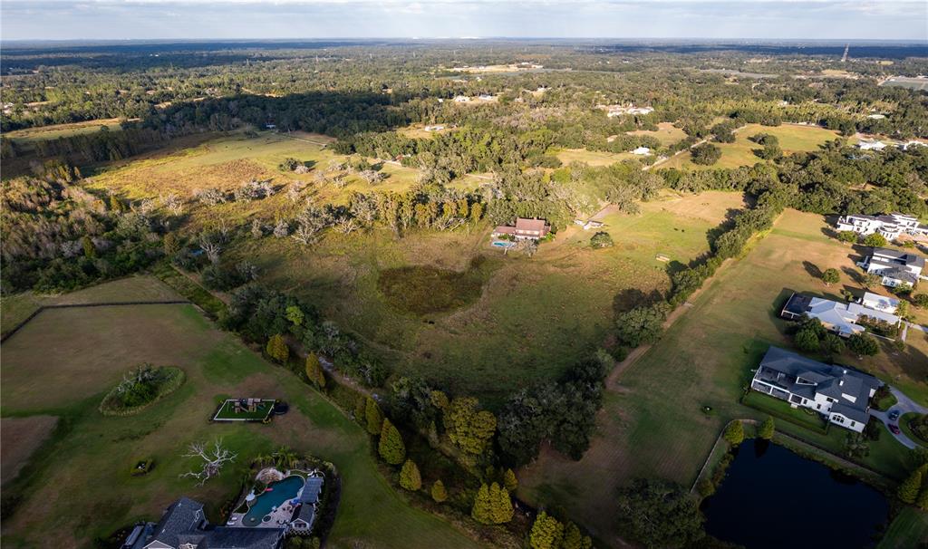 An aerial view shows a large rural property with a house, pool, and surrounding fields — 12537 TOMAR DRIVE, THONOTOSASSA, FL