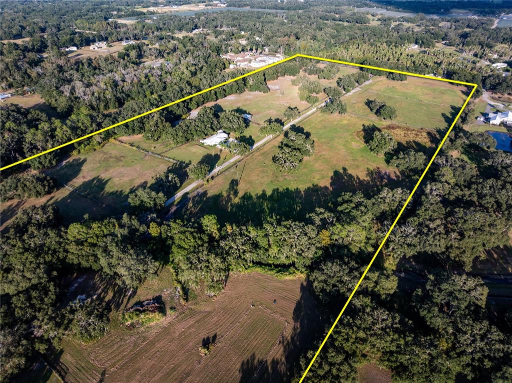 An aerial view shows a large, fenced rural property with a house and scattered trees — 12537 TOMAR DRIVE, THONOTOSASSA, FL