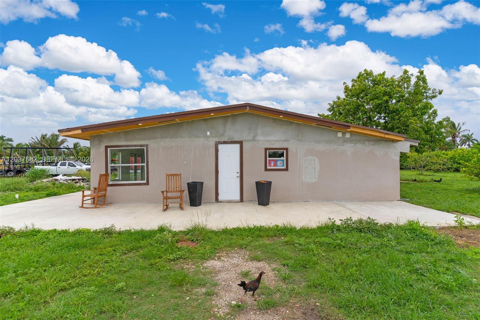 A single-story house with a concrete patio, two rocking chairs, and a chicken in front — 20304 SW 186th St, Miami FL 33187, MIAMI, FL