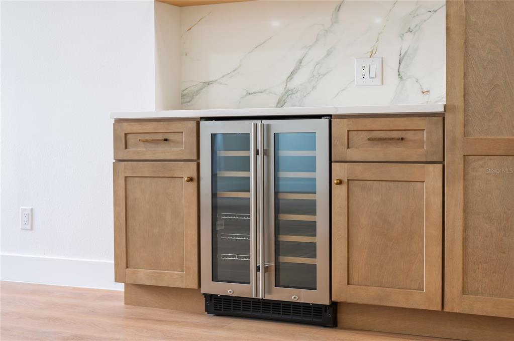 A kitchen wet bar features wooden cabinets, a marble backsplash, and a dual-zone wine refrigerator — 2424 STONE CROSS CIRCLE, ORLANDO, FL