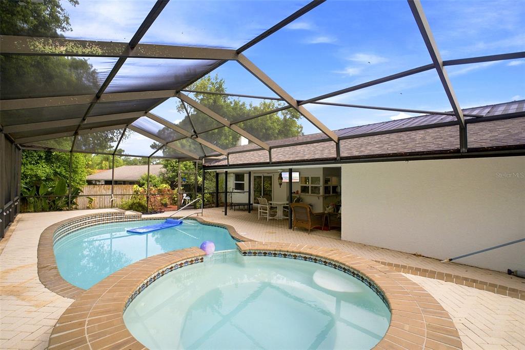 A screened-in patio features a swimming pool, a circular spa, and brick paver decking — 1071 PERSIMMON DRIVE, PALM HARBOR, FL