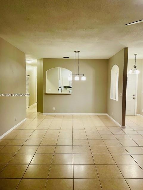 A dining area with tile flooring, a modern light fixture, and a kitchen pass-through window — DEERFIELD BEACH, FL