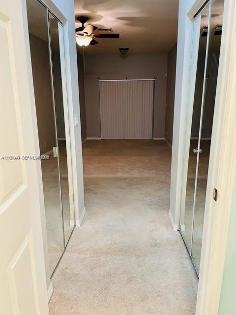 A carpeted hallway leads to a room with mirrored closet doors and vertical blinds — DEERFIELD BEACH, FL