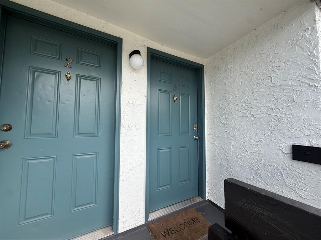 Two teal apartment doors labeled 2 and 3 sit side-by-side on a textured white wall — 4111 S SEMORAN BOULEVARD UNIT 3, ORLANDO, FL