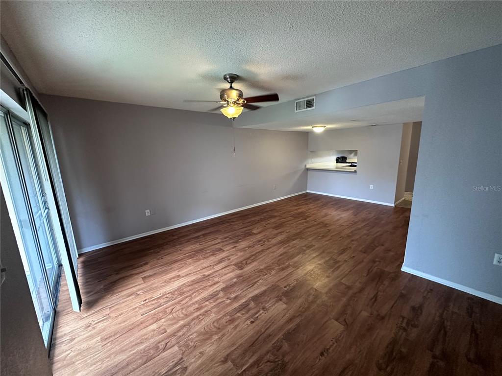 An empty living room features wood-look flooring, gray walls, a ceiling fan, and sliding doors — 4111 S SEMORAN BOULEVARD UNIT 3, ORLANDO, FL