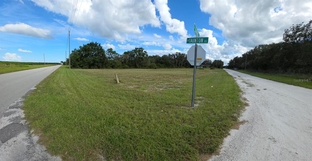A vacant corner lot features a street sign for Taunton Road and a stop sign — 500 N BARRIE ROAD, AVON PARK, FL
