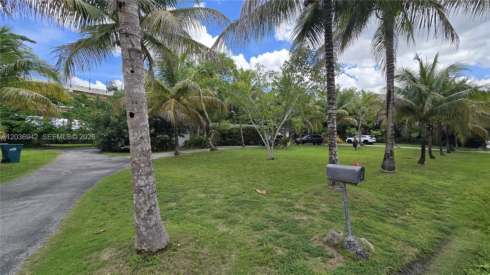 A grassy front yard features several palm trees, a mailbox, and a paved driveway — 8603 SW 68th St Rd, Miami FL 33143, MIAMI, FL