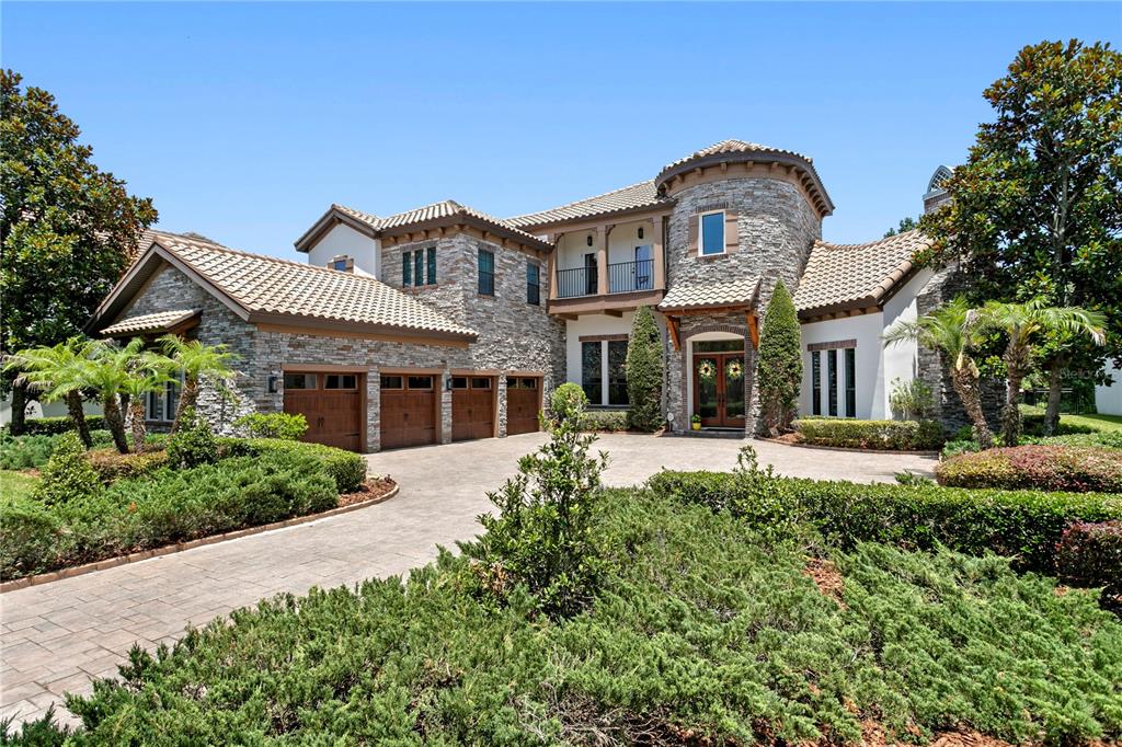 A large, two-story stone and stucco house with a multi-car garage and landscaped front yard — 15306 FISHHAWK PRESERVE DRIVE, LITHIA, FL