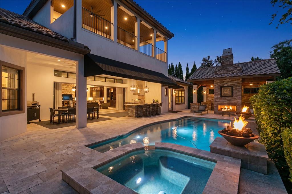 A backyard patio features a swimming pool, hot tub, outdoor kitchen, and stone fireplace — 15306 FISHHAWK PRESERVE DRIVE, LITHIA, FL