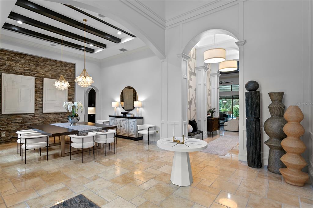 A dining area and foyer feature stone walls, dark ceiling beams, and light tile flooring — 15306 FISHHAWK PRESERVE DRIVE, LITHIA, FL