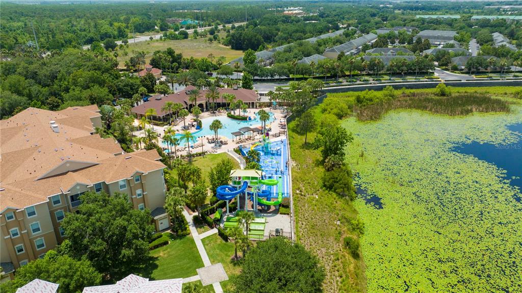 An aerial view shows a resort-style swimming pool, water slides, and a large lake — 2813 ALMATON LOOP UNIT 301, KISSIMMEE, FL