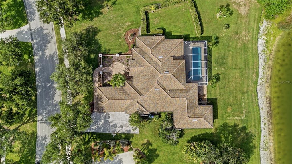 An aerial view shows a house with a tiled roof, a screened pool, and landscaping — 7389 S SERENOA DRIVE, SARASOTA, FL
