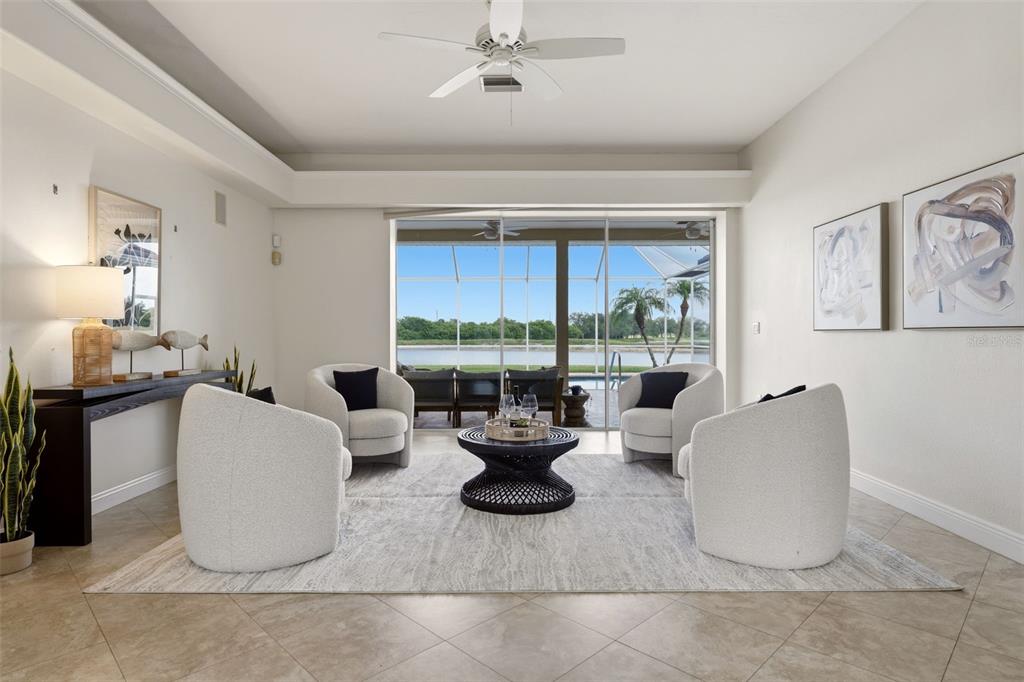 A living room features four white armchairs, a dark coffee table, and a lake view — 7389 S SERENOA DRIVE, SARASOTA, FL