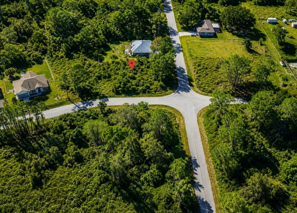 An aerial view shows a house and a vacant wooded lot at a road intersection — 1600 WALDO STREET SE, PALM BAY, FL