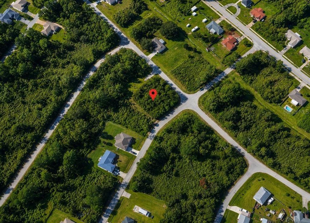An aerial view shows a vacant, wooded lot marked with a red pin — 1600 WALDO STREET SE, PALM BAY, FL