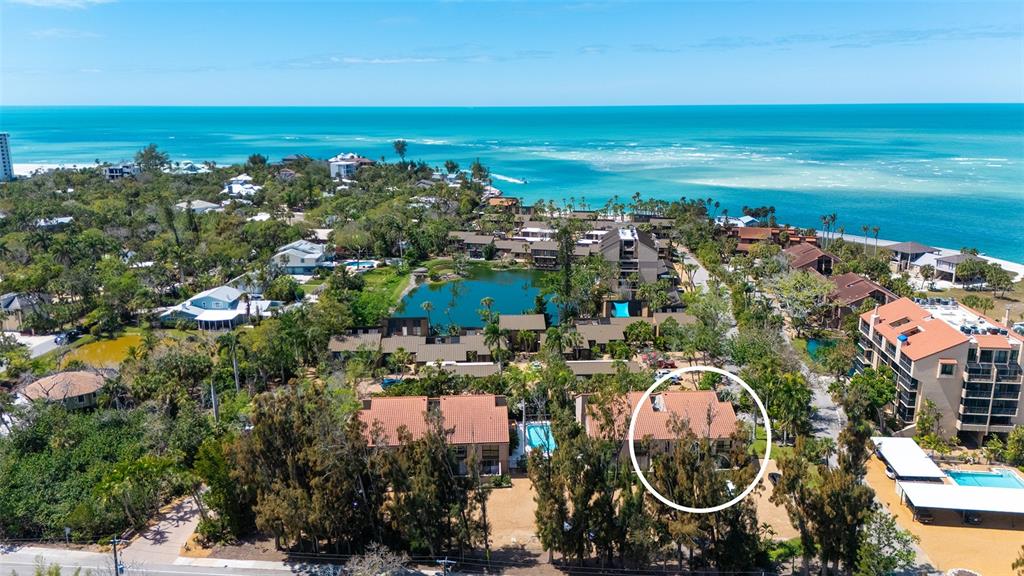 An aerial view shows a multi-story residential building with a red tile roof — 115 PASS KEY ROAD UNIT 115, SARASOTA, FL