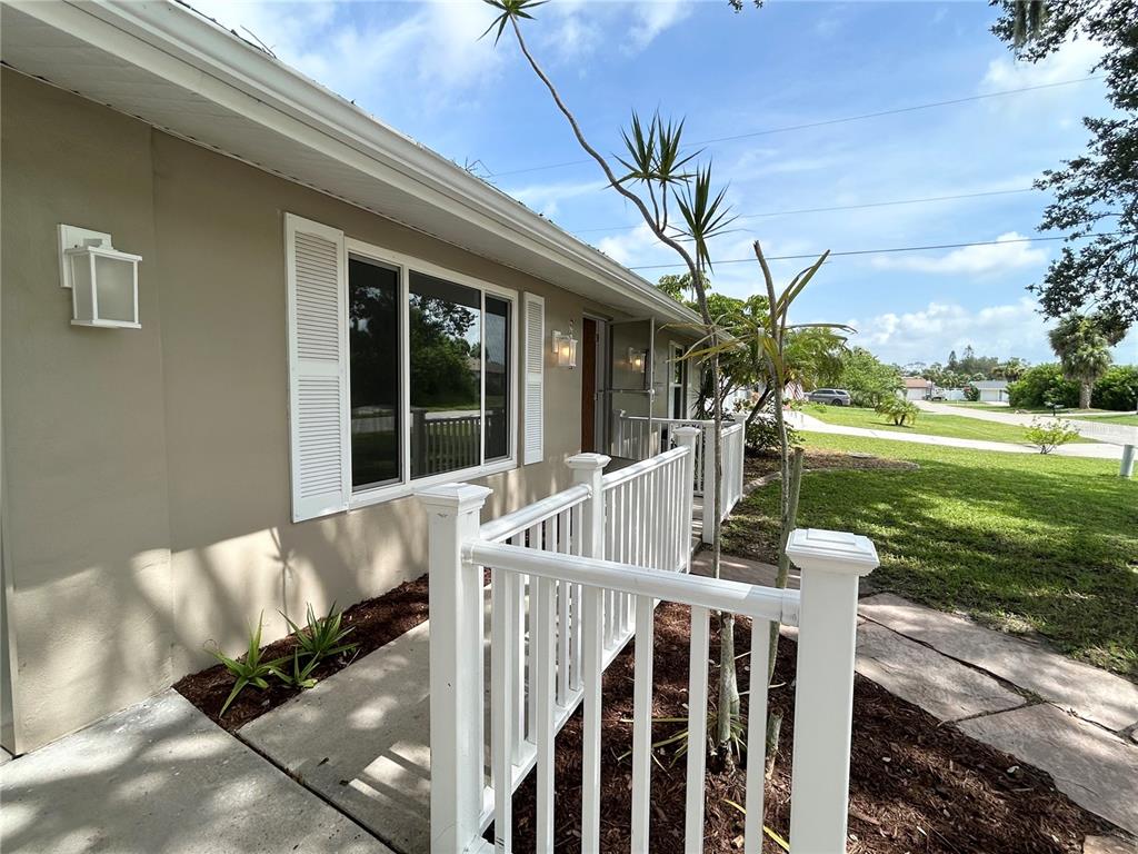A tan house exterior features a white railing, a window with shutters, and landscaping — 4485 COSTELLO STREET, PORT CHARLOTTE, FL