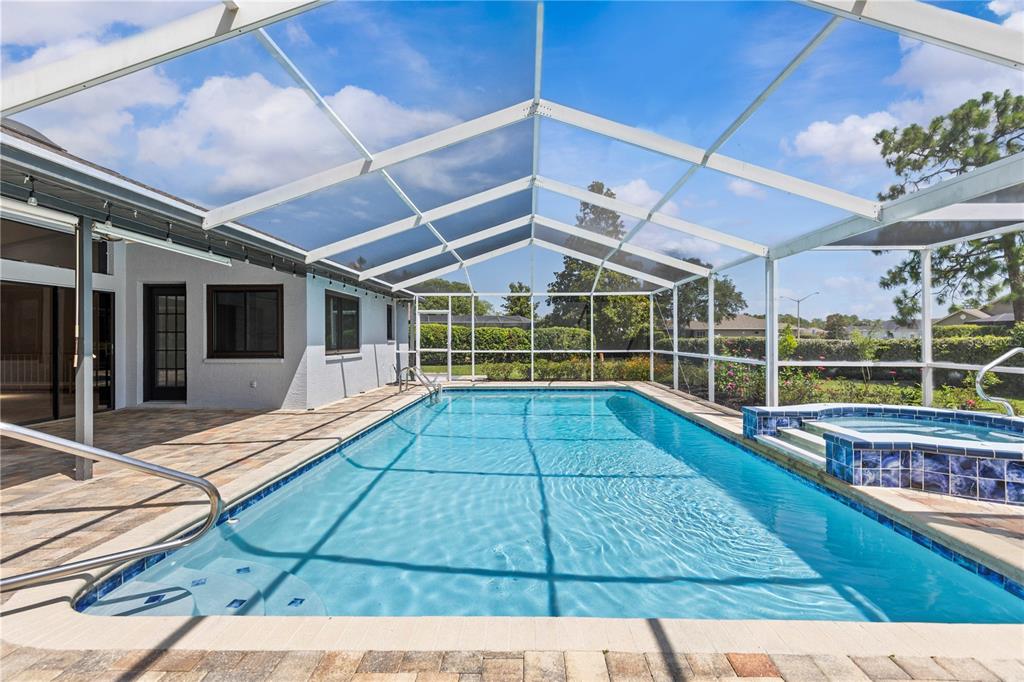 A swimming pool and attached spa are enclosed within a screened-in lanai with pavers — 9447 ASHLEY DRIVE, WEEKI WACHEE, FL