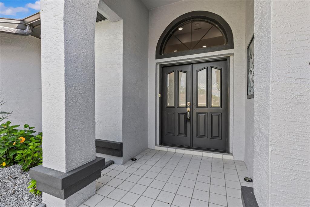 A covered entryway features a double front door with glass panels and an arched transom window — 9447 ASHLEY DRIVE, WEEKI WACHEE, FL
