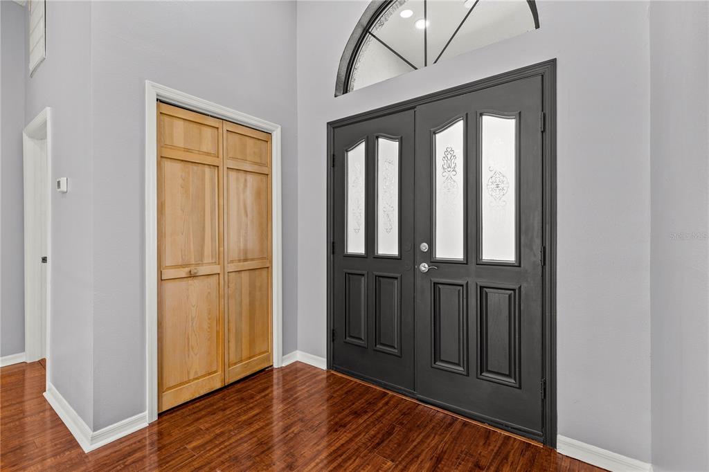 An entryway features dark double front doors, a light wood closet, and hardwood flooring — 9447 ASHLEY DRIVE, WEEKI WACHEE, FL