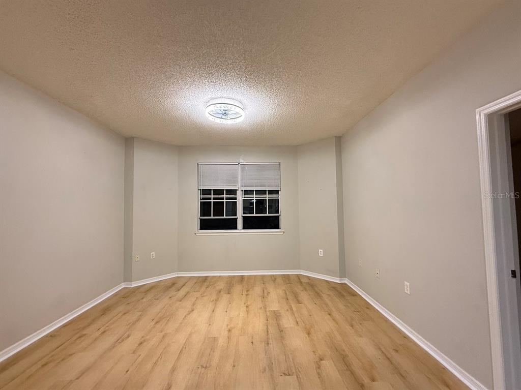 An empty room with light-colored walls, wood-look flooring, and a single window with blinds — 10831 WINDSOR WALK DRIVE UNIT 1305, ORLANDO, FL