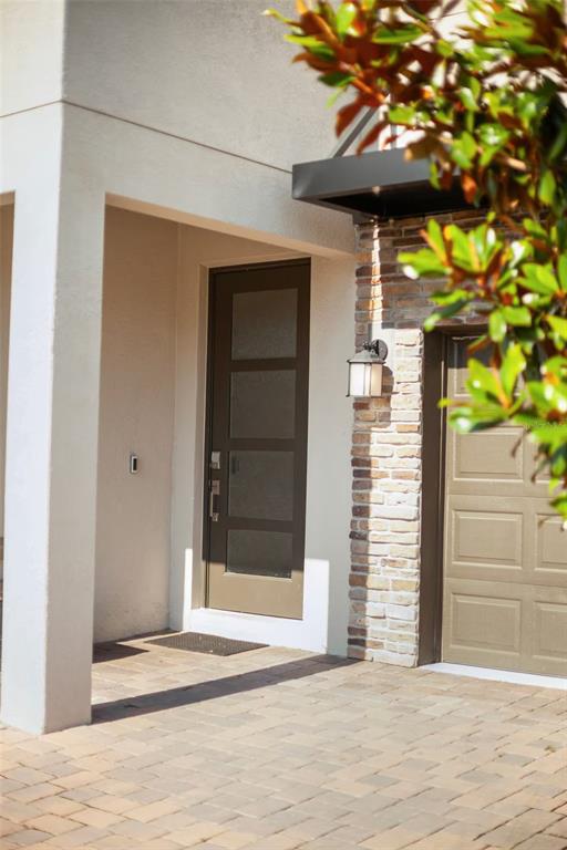 A front entrance features a modern door, brick siding, a wall lantern, and paved driveway — 1069 LEADER STREET, DAVENPORT, FL