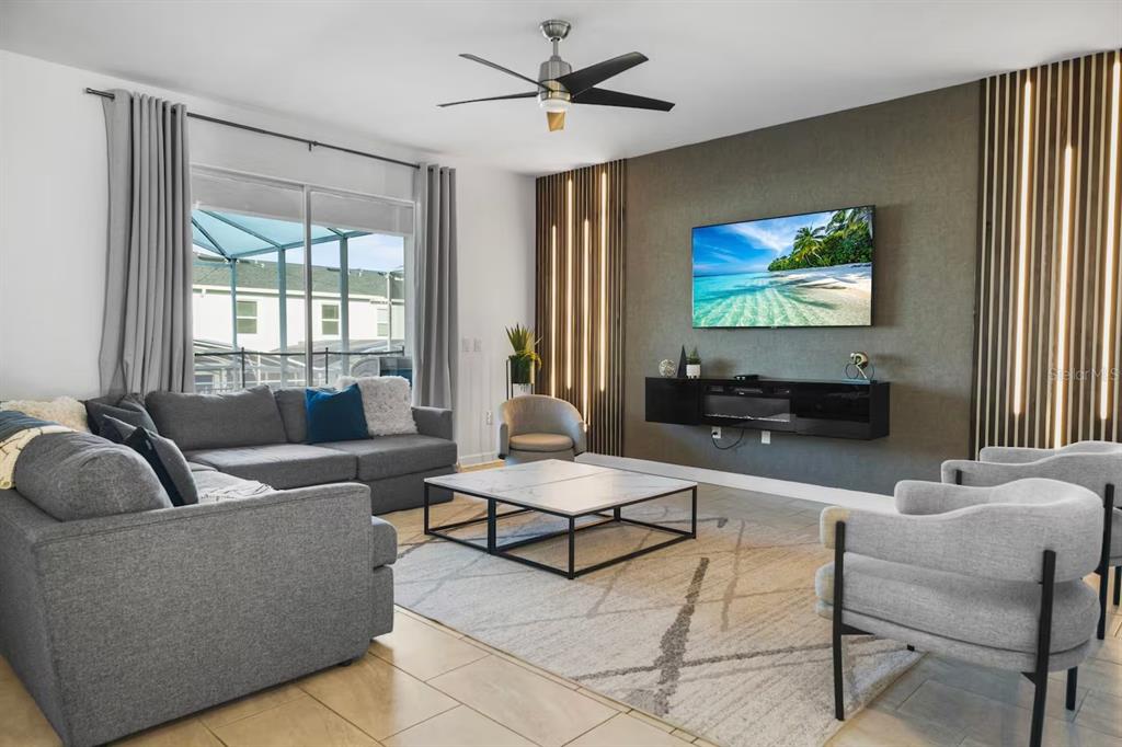 A living room features a gray sectional sofa, two armchairs, and a wall-mounted television — 1069 LEADER STREET, DAVENPORT, FL