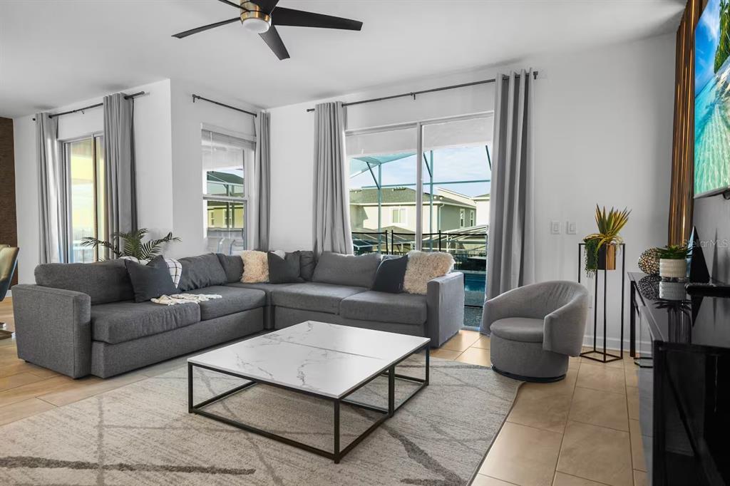 A living room features a gray sectional sofa, marble coffee table, and sliding glass doors — 1069 LEADER STREET, DAVENPORT, FL