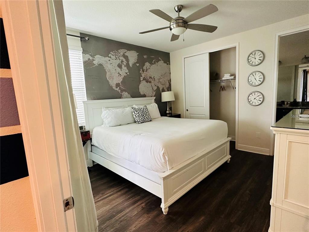 A bedroom features a white bed, a world map wall mural, and three wall clocks — 241 FALLS DRIVE, KISSIMMEE, FL