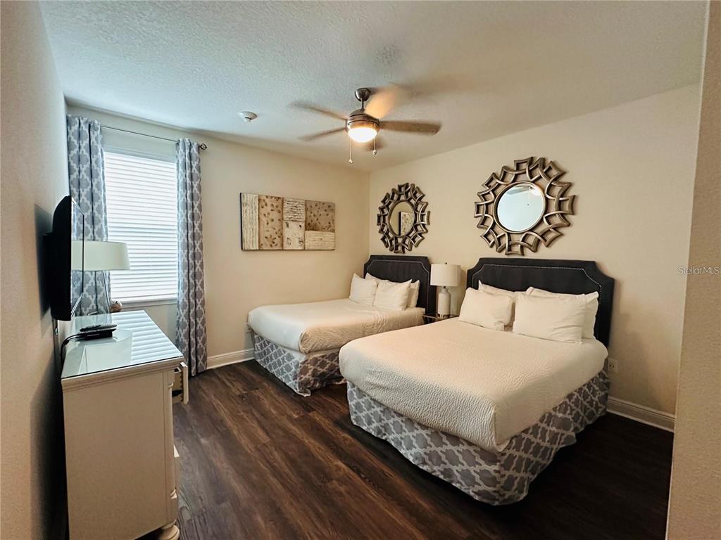 A bedroom features two beds, a dresser, a ceiling fan, and two decorative wall mirrors — 241 FALLS DRIVE, KISSIMMEE, FL