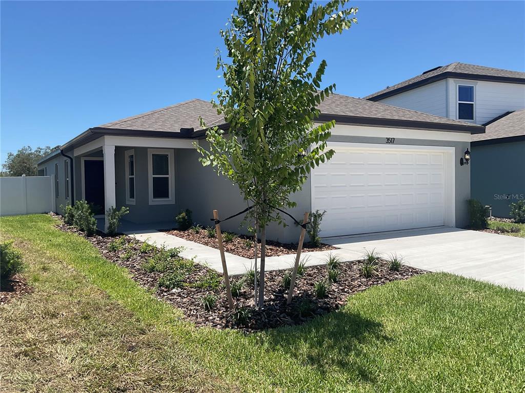 A single-story house with a gray exterior, a two-car garage, and a landscaped front yard — 3517 HORNBEAM ROAD, SPRING HILL, FL
