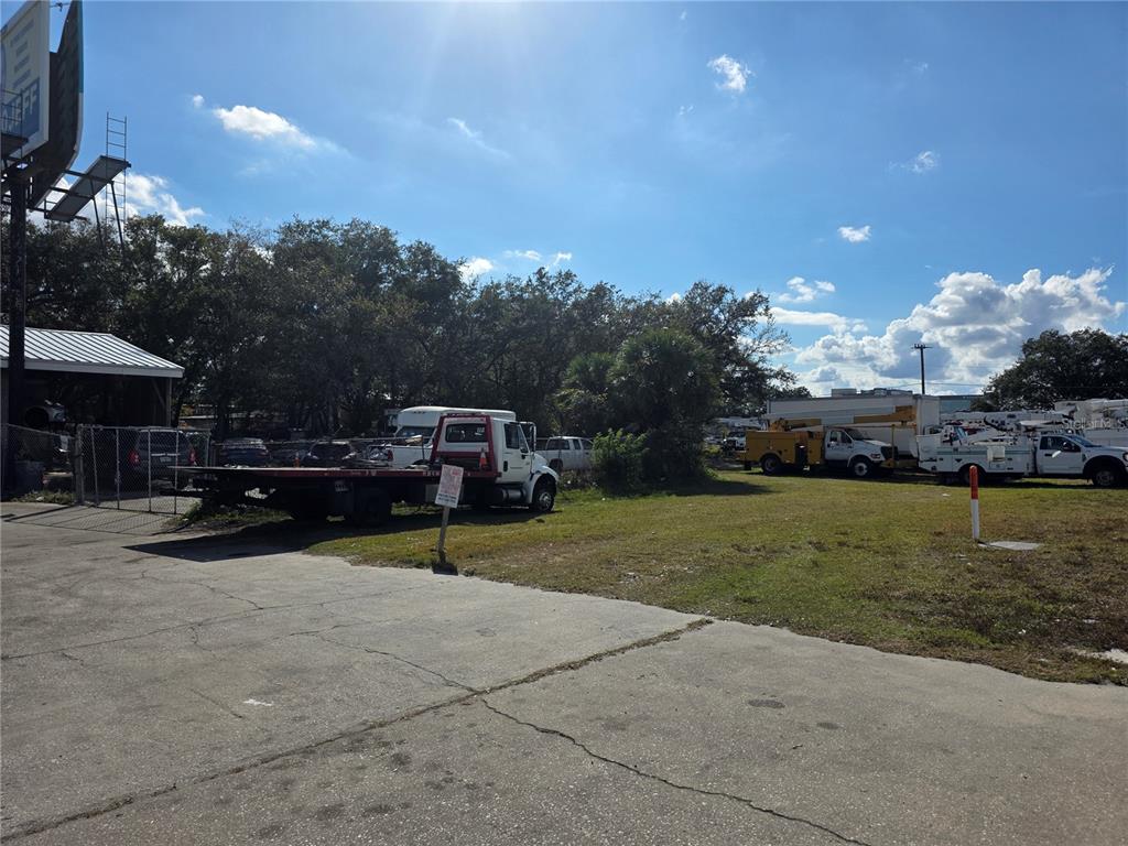 A paved lot with a parked tow truck and utility vehicles under a sunny sky — 410 E DONEGAN AVENUE, KISSIMMEE, FL
