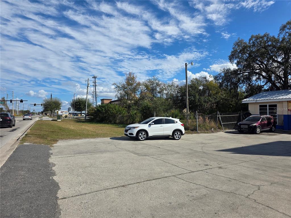 A white SUV is parked on a concrete lot next to a grassy area — 410 E DONEGAN AVENUE, KISSIMMEE, FL