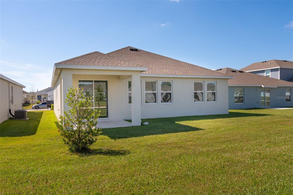 The exterior rear view of a single-story house with a covered patio and lawn — 4223 LITTLE OWL LANE, KISSIMMEE, FL