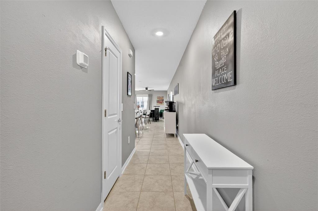 A tiled hallway leads from an entryway past a white console table toward an open living area — 4394 BABBLING BROOK WAY, KISSIMMEE, FL