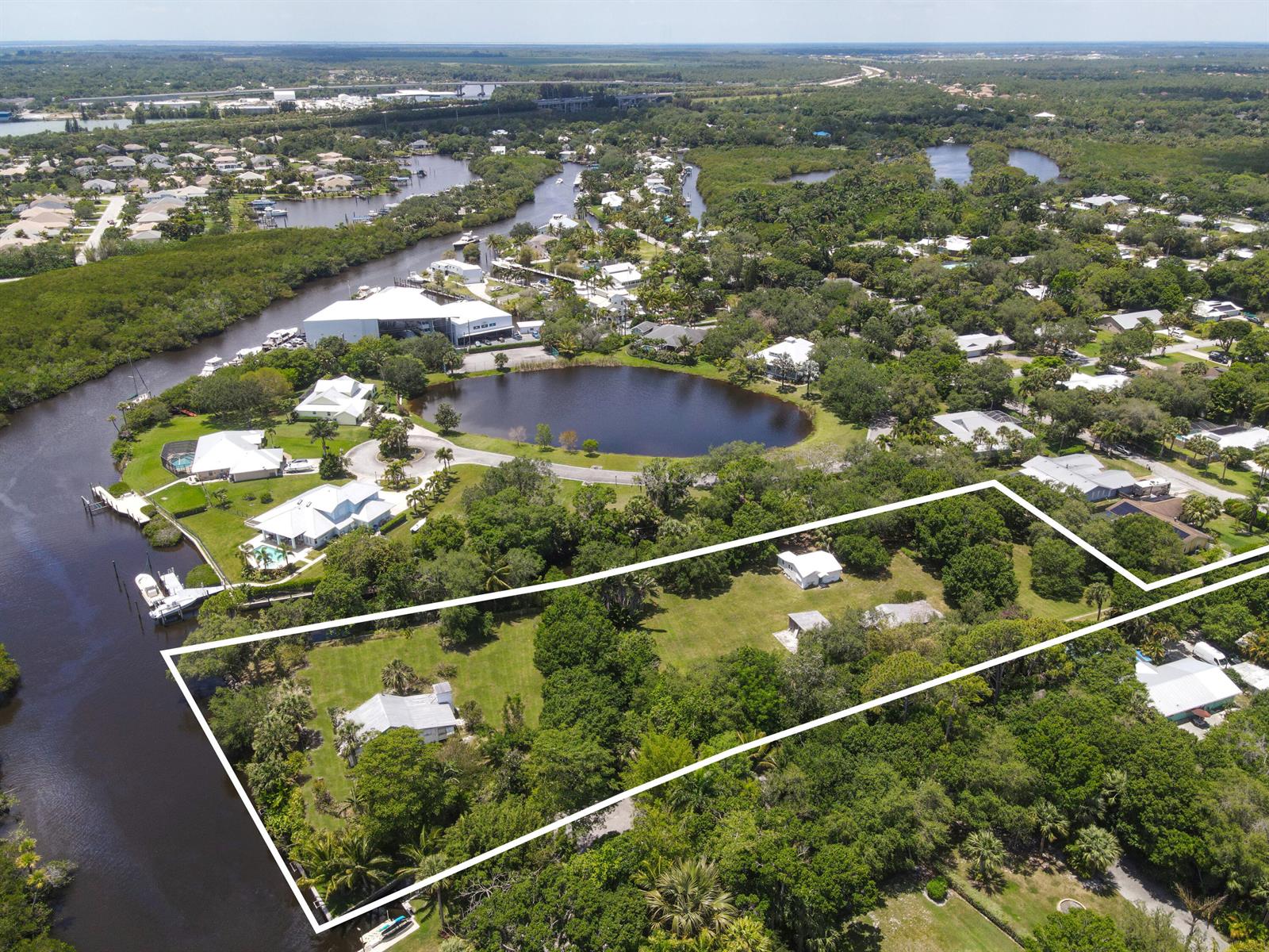 An aerial view shows a large, wooded residential lot with several buildings near a waterway — 332 SW Salerno Road, Stuart FL 34997, STUART, FL