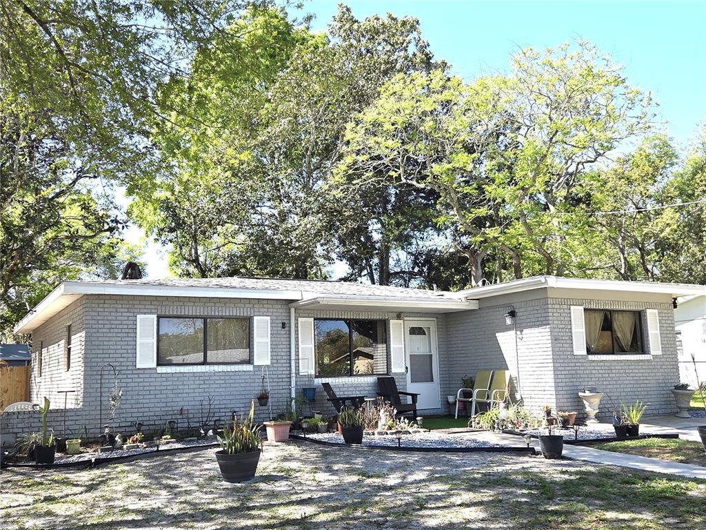 A single-story gray brick house with white shutters and a gravel front yard — 21390 LEHOUIER DRIVE, BROOKSVILLE, FL