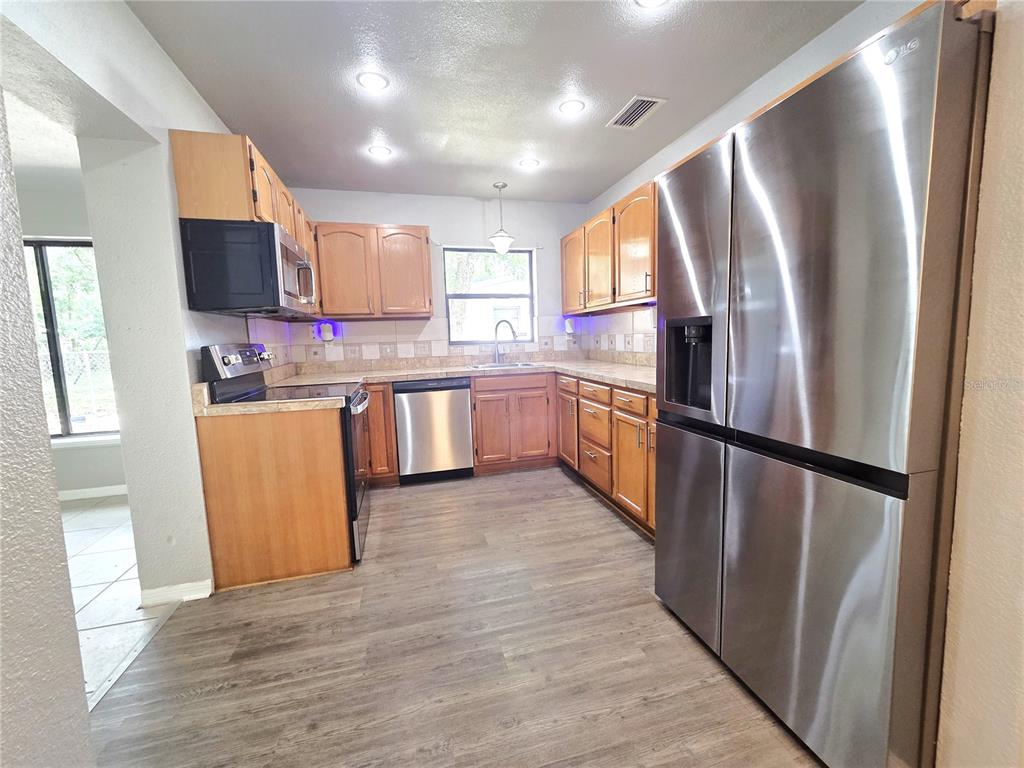 A kitchen features wood cabinets, stainless steel appliances, and wood-look flooring — 21390 LEHOUIER DRIVE, BROOKSVILLE, FL